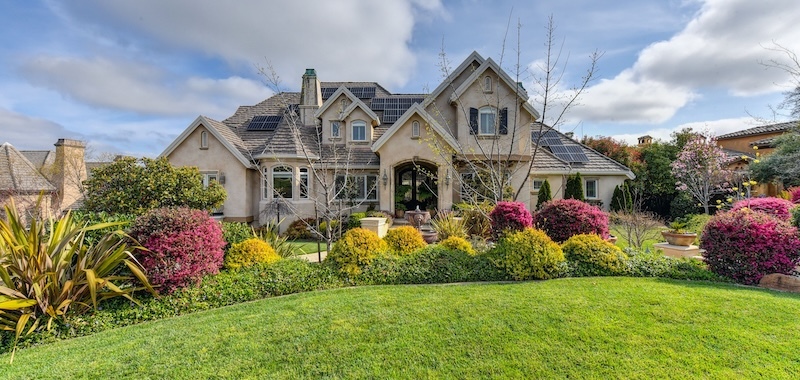 suburban house surrounded by flowering azaleas, phormium, vinca, and euonymus